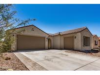 Stunning home exterior featuring a three car garage and a beautiful terra cotta tile roof at 2373 N Riverside Dr, Florence, AZ 85132