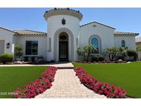 Charming home featuring a turret entry, beautiful landscaping, and a brick walkway lined with vibrant pink flowers at 3675 E Strawberry Dr, Gilbert, AZ 85298