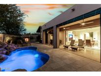 Inviting backyard pool and patio with rock waterfall feature, fireplace, lounge seating, and seamless indoor/outdoor living at 27708 N 110Th Pl, Scottsdale, AZ 85262