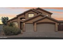 Inviting two-story home with a three-car garage and well-manicured landscaping, set against a vibrant sunset sky at 11263 S Oakwood Dr, Goodyear, AZ 85338