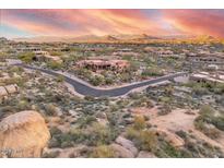 Expansive aerial view of desert homes surrounded by natural rock formations and mountains under colorful sunset skies at 10671 E Hedgehog Pl, Scottsdale, AZ 85262
