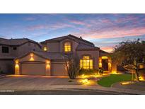 Inviting home with manicured landscaping, three-car garage, and warm exterior lighting at sunset at 4235 W Harrison St, Chandler, AZ 85226