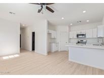 Open-concept living room and kitchen boasts wood-look floors, modern appliances, and white cabinets at 463 W Taylor Ave, Coolidge, AZ 85128