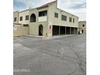 An apartment building exterior featuring tan stucco, arched entryways, and convenient parking at 5987 N 48Th Dr, Glendale, AZ 85301