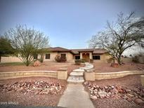 Charming single-story home with desert landscaping, rock features, and inviting stairway entrance at 13007 W Tuckey Ct, Glendale, AZ 85307