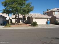 Well-maintained single-story home featuring a lush front yard and a two-car garage at 1306 W Charleston Ave, Phoenix, AZ 85023