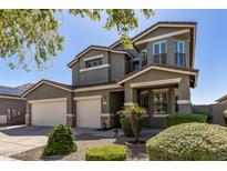 Two-story home featuring a well-manicured front yard and a three-car garage, providing ample parking and curb appeal at 13545 W Caribbean Ln, Surprise, AZ 85379