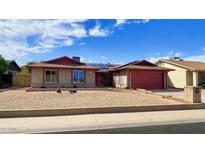 Charming single-story brick home with a red trim, gravel yard, and solar panels under a clear blue sky at 13834 N 39Th Ln, Phoenix, AZ 85053