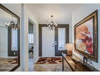 Inviting foyer with neutral tile flooring, decorative lighting, and a statement mirror and artwork at 32241 N Dog Leg Ct, San Tan Valley, AZ 85143