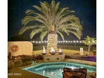 Inviting pool area with decorative fire bowls and a lighted palm tree, perfect for nighttime ambiance at 32241 N Dog Leg Ct, San Tan Valley, AZ 85143