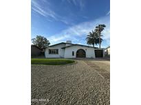 Charming single-story home featuring a rounded entryway, chimney, desert landscaping, and a separate garage at 113 W Rawhide Ave, Gilbert, AZ 85233