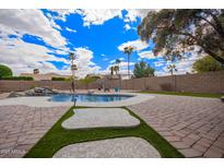 The backyard features a luxurious pool, lush greenery, and a charming pergola for outdoor enjoyment at 14609 W Marcus Dr, Surprise, AZ 85374