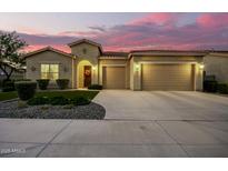 Charming home with a three-car garage and beautifully landscaped front yard under a colorful sky at 18938 W Luke Ave, Litchfield Park, AZ 85340