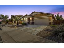 Beautiful single-Gathering home featuring a two-car garage, desert landscaping, and warm exterior lighting at 21609 N Diamond Dr, Maricopa, AZ 85138