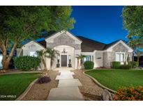 Charming home with stone accents, lush landscaping, and a welcoming walkway, enhanced by elegant outdoor lighting at 23420 S 202Nd St, Queen Creek, AZ 85142