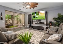 Comfortable living room with large-screen TV, stylish furnishings, and sliding doors to the outdoor patio at 3518 S Posse Trl, Gilbert, AZ 85297