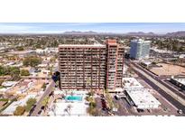 A high-rise condo building with a pool and palm trees, set against a backdrop of city and distant mountains at 4750 N Central Ave # 12H, Phoenix, AZ 85012