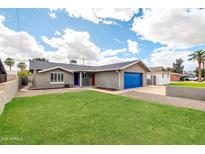 A well-maintained single-story home showcasing its manicured front lawn and blue garage door at 8637 E Jackrabbit Rd, Scottsdale, AZ 85250