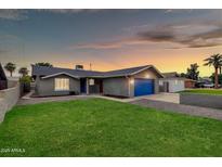 Charming single-story home featuring a well-maintained lawn and a brightly colored garage door at 8637 E Jackrabbit Rd, Scottsdale, AZ 85250