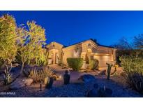 Warm lighting showcases a desert-landscaped home with neutral tones and well-manicured shrubs at twilight at 9431 N Summer Hill Blvd, Fountain Hills, AZ 85268