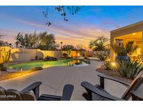 Stunning outdoor pool area with a waterfall feature, fire pit, and lounge chairs at sunset at 9727 E Presidio Rd, Scottsdale, AZ 85260