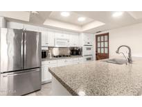 Well-lit kitchen featuring granite countertops, stainless steel appliances, and white cabinetry at 3832 W Davidson Ln, Phoenix, AZ 85051