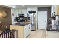 Bright kitchen featuring white cabinetry, stainless steel appliances, granite counters, and tile floors at 9814 W Shasta Dr, Sun City, AZ 85351
