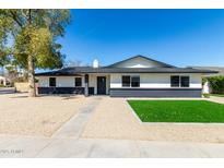 Charming single-story home with a well-maintained gravel yard and contrasting black and white exterior paint at 1504 E Jasmine St, Mesa, AZ 85203