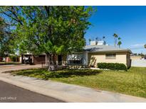 Charming home featuring a lush lawn, mature tree, and a covered carport, all under a clear blue sky at 1320 W Mariposa St, Phoenix, AZ 85013