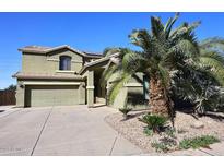 Home featuring a three-car garage, desert landscaping, and a palm tree at 1765 N Agave St, Casa Grande, AZ 85122