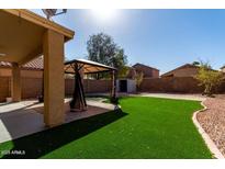 Spacious backyard with artificial grass, stone landscaping and gazebo-covered patio area at 41955 W Hillman Dr, Maricopa, AZ 85138