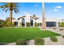 Charming home showcasing a lush lawn, mature palm trees, and modern architectural design at 8206 E Del Camino Dr, Scottsdale, AZ 85258