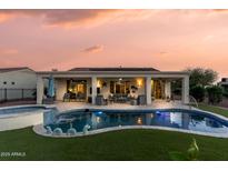 Backyard pool and spa with outdoor living space, covered patio and lush artificial grass at twilight at 13616 W Junipero Dr, Sun City West, AZ 85375