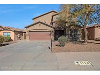 Charming two-story home showcasing a brown exterior, spacious driveway, and well-maintained landscaping at 1713 S 117Th Dr, Avondale, AZ 85323