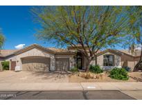 Charming single-story home featuring a well-manicured front yard and a three-car garage at 6438 E Montreal Pl, Scottsdale, AZ 85254