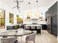 Bright kitchen with island, dining area, stainless steel appliances, and dark cabinets at 6438 E Montreal Pl, Scottsdale, AZ 85254