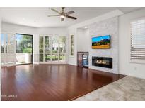 Bright living room with hardwood floors, modern fireplace, and open shutters to the outdoor view at 8989 N Gainey Center Dr # 149, Scottsdale, AZ 85258