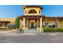 Stunning home entrance with a tower, arched doorway, stone steps, and lovely landscaping, creating a welcoming approach at 9716 E Mariposa Grande Dr, Scottsdale, AZ 85255