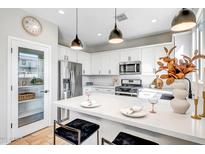 Bright, white kitchen with stainless steel appliances and a large island featuring stylish pendant lighting at 10823 W Polk St, Avondale, AZ 85323