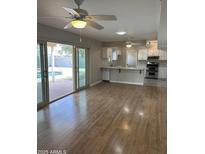 Open concept living room view into kitchen, overlooking pool area with natural light and hardwood flooring at 1172 E Delano Dr, Casa Grande, AZ 85122