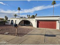 Charming single-story home boasts a red garage door, unique architecture and a well-kept, desert-friendly landscaped front yard at 8227 N 47Th Dr, Glendale, AZ 85302