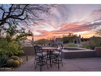 Outdoor patio featuring a dining set and spa, surrounded by desert landscaping and beautiful sunset views at 41353 N 106Th St, Scottsdale, AZ 85262