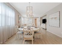 An inviting dining area features a round table and decorative light fixture, seamlessly flowing into the living space at 9910 E Theia Dr, Mesa, AZ 85212
