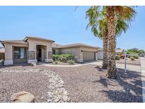 Charming home featuring desert landscaping, natural rock features, and mature palm trees at 14837 W Crocus Dr, Surprise, AZ 85379