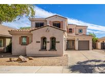 Two-story home featuring desert landscaping, warm earthy tones, and a tile roof at 17423 W Yavapai St, Goodyear, AZ 85338