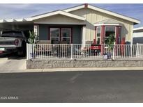 Charming single-story home featuring a covered porch with a white picket fence and outdoor seating at 3504 N Hawes Rd # 3504, Mesa, AZ 85207