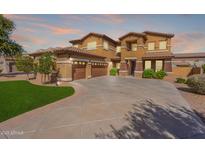 Inviting two-story home showcasing a spacious driveway, lush landscaping and a three-car garage at 18436 E Celtic Manor Dr, Queen Creek, AZ 85142