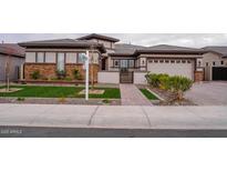 Charming single-story home featuring a brick-accented facade, manicured lawn, and a welcoming paver walkway at 18925 W Windsor Blvd, Litchfield Park, AZ 85340