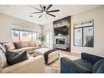 Comfortable living room featuring a stone fireplace, plush seating, and a modern ceiling fan at 3904 E Carter Dr, Phoenix, AZ 85042