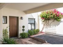 Inviting covered front entry with mature landscaping, brick accents, and a solid wood front door at 5101 N Casa Blanca Dr # 217, Paradise Valley, AZ 85253